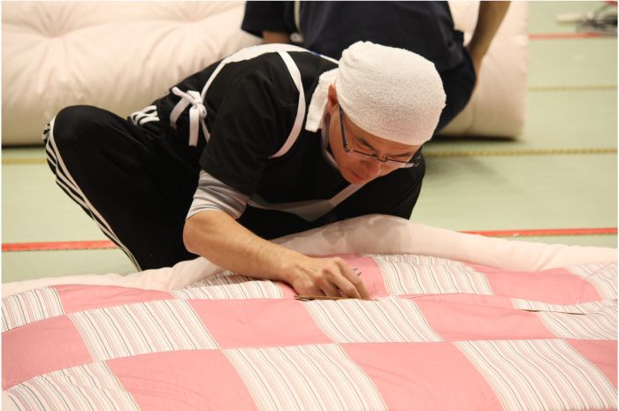 畳の上で四つん這いになって、朝から晩まで働く布団職人は、手首やひざの痛み、腰痛など職業病を抱えます